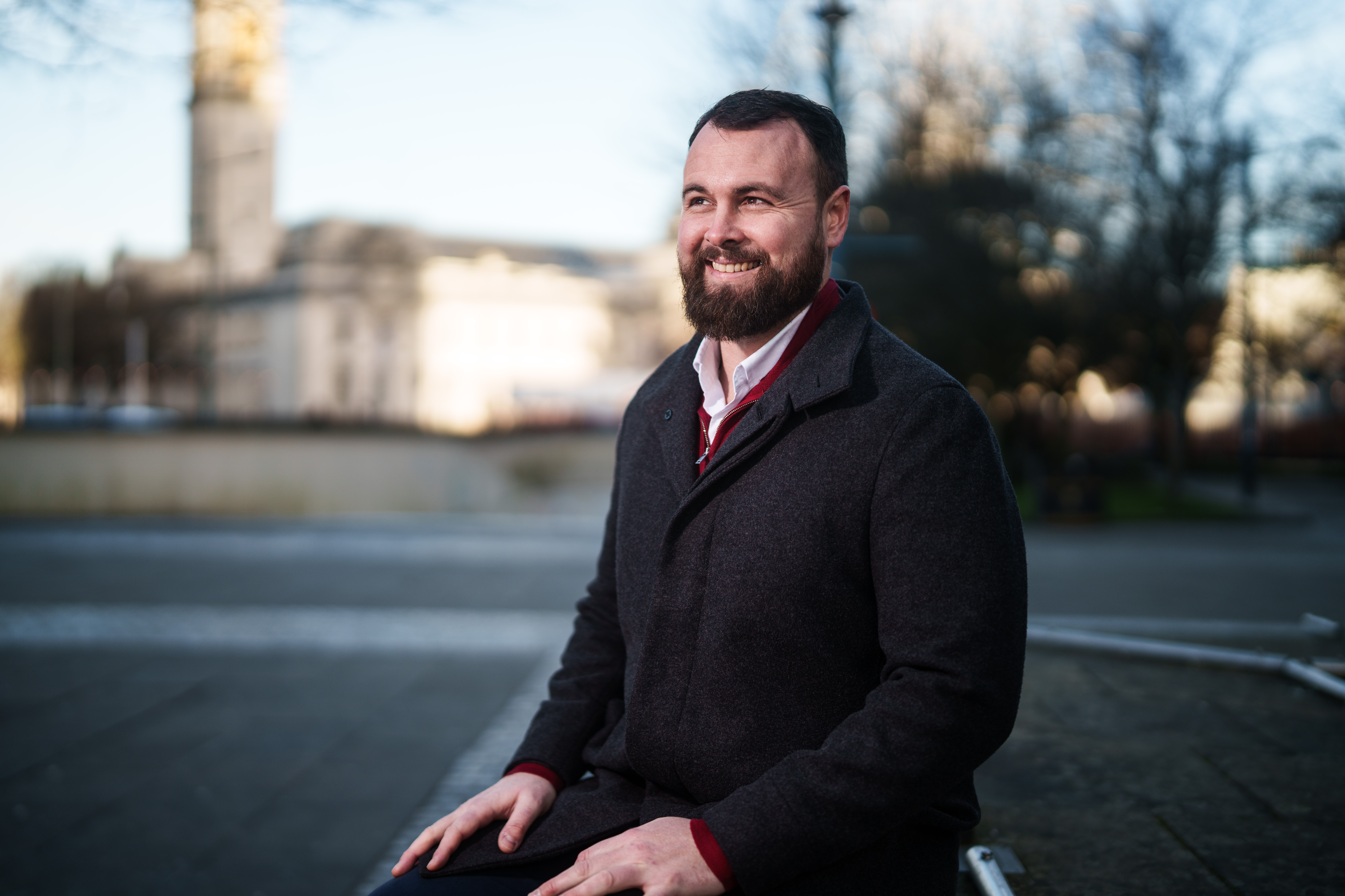 Chris sat down outdoors. Cardiff city hall is in the background
